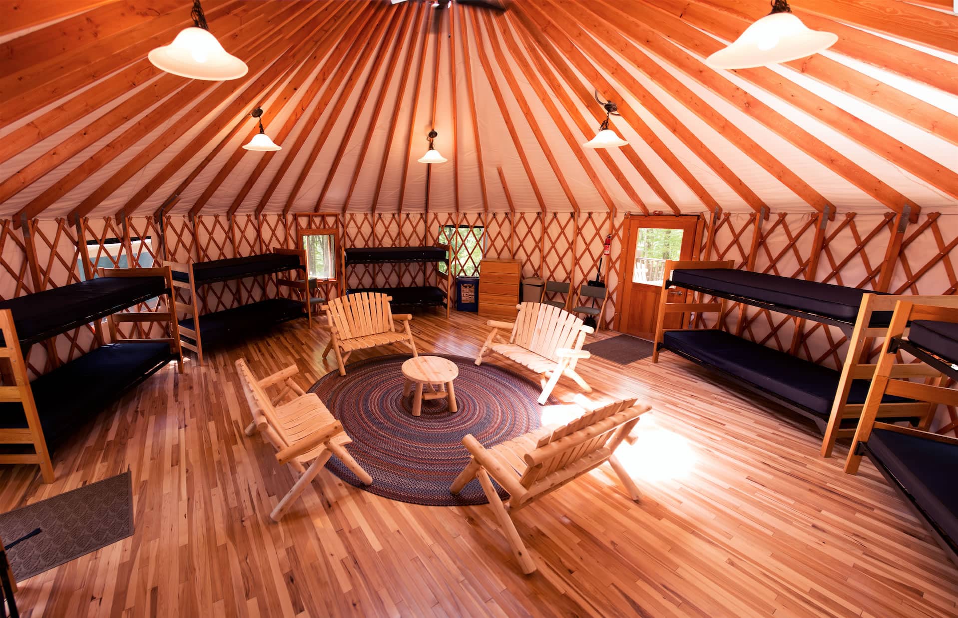 Rustic yurt gathering space with built-in bunk beds and wooden beams