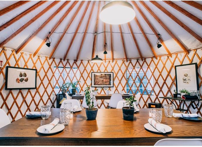 Modern yurt dining area with contemporary furniture and natural wood ceiling